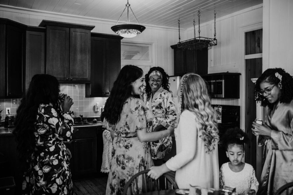Getting ready images in a kitchen for The Clearing wedding in Shedden, ON. The bridal party is laughing in matching wedding robes.