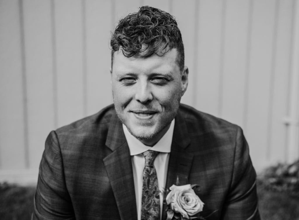 Black and white groom portrait. Close up and groom is smiling at the camera.