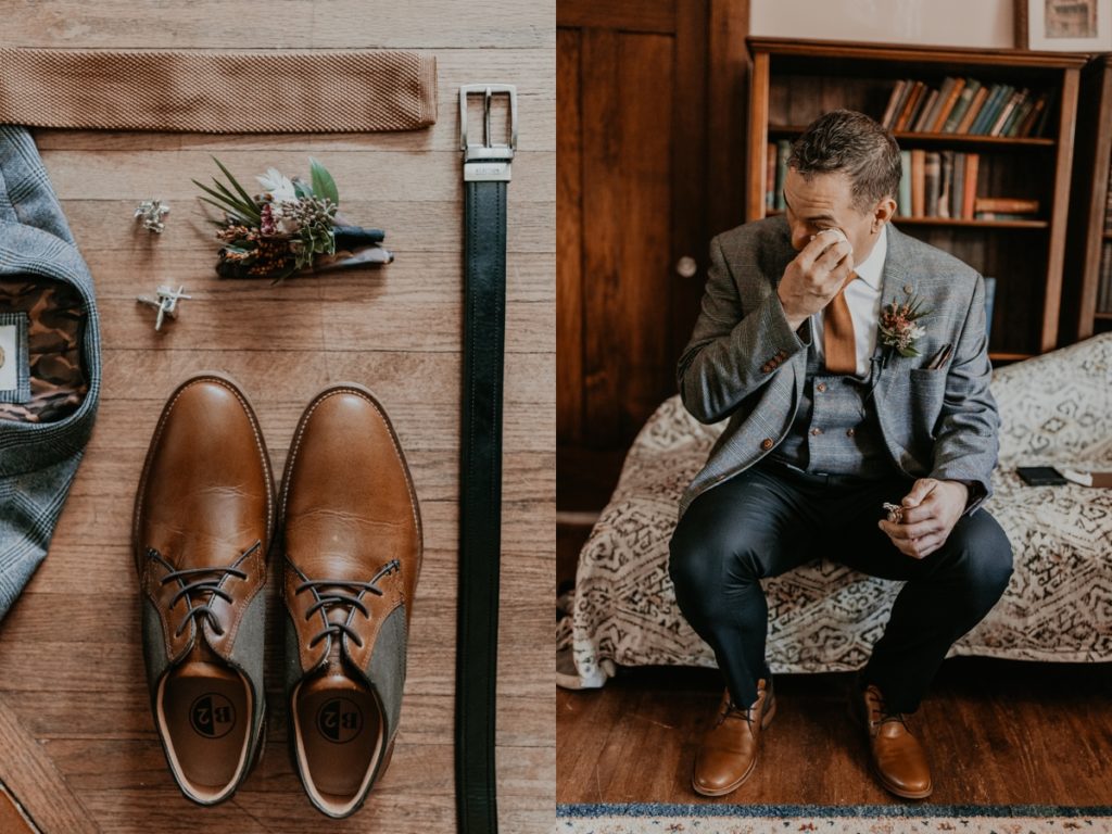Groom is sitting on the side of a bed and wipes a tear from his eye after opening a gift from his bride before his Elsie Perrin Williams Estate wedding in London, ON. Captured by top London, Ontario wedding photographer Ashlee Ellison.