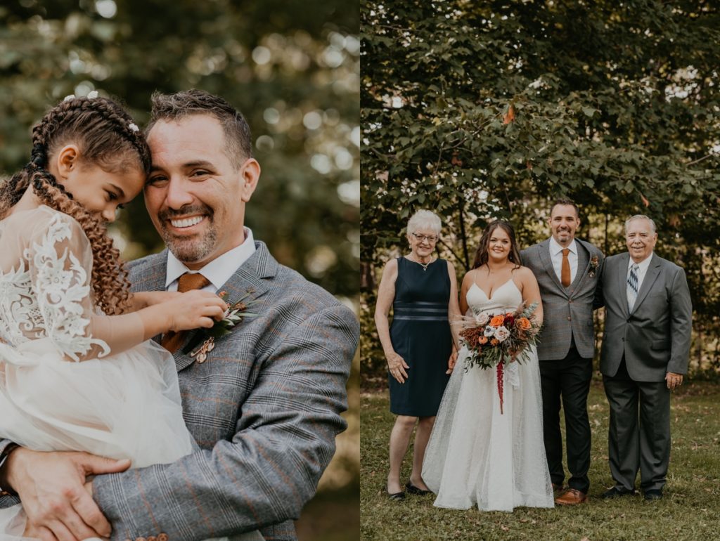 Groom lifts his stepdaughter and flower girl for a candid photo. The groom is smiling at the camera. the flower girl's head is rested against the groom's temple and she is playing with his boutonniere.