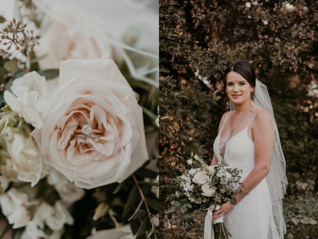 Bride is standing side-profile to the camera and looking over her shoulder and smiling at the camera. She is holding a bouquet of roses and anemones in front of greenery at Cellar 52 in St Jacobs Ontario