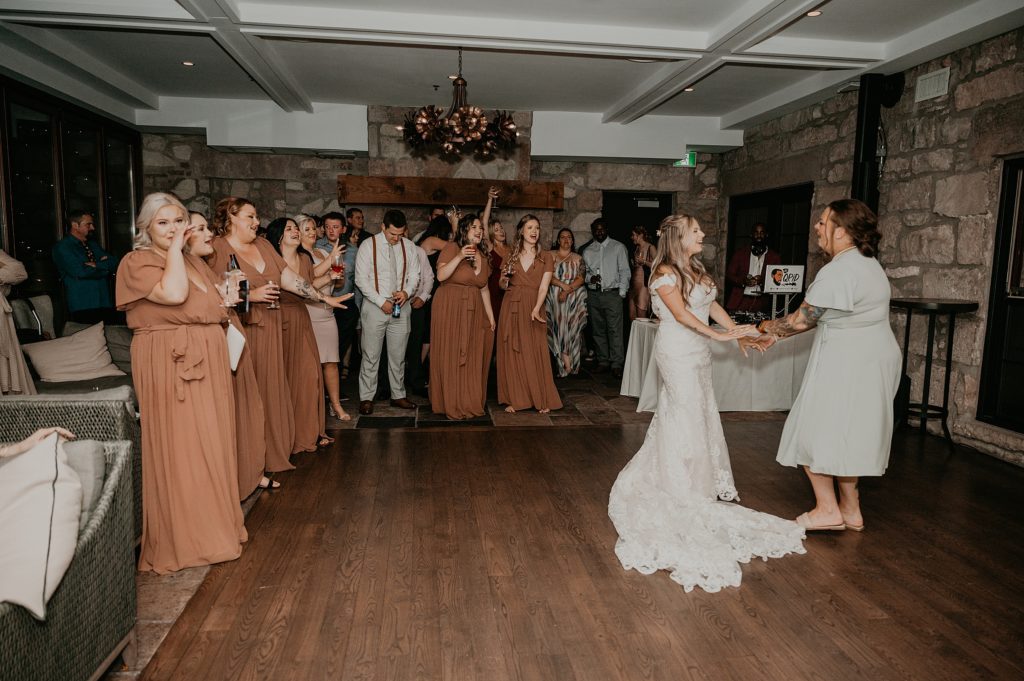 Bride and her mom share an upbeat dance as wedding guests look on. Captured at the Cambridge Mill by top cambridge wedding photographer ashlee ellison.