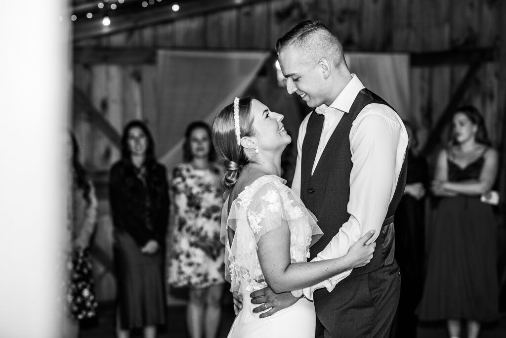 Bride looks up at her smiling groom as they share their first dance at the century barn in denfield, ontario.