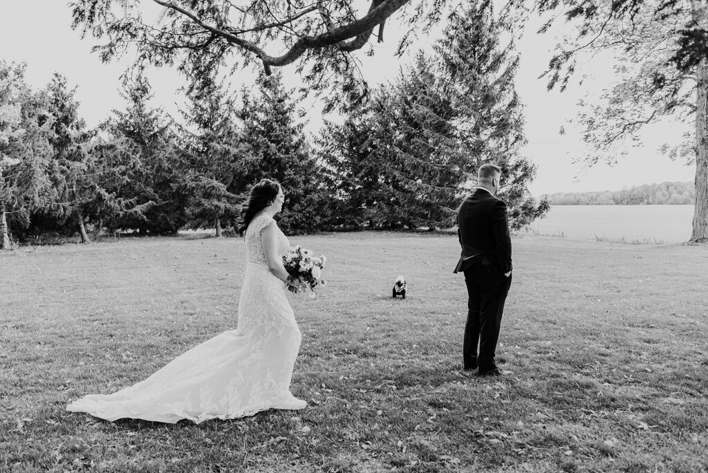 Black and white image of bride approaching groom for a first look photo on the grounds of crescent hill acres.