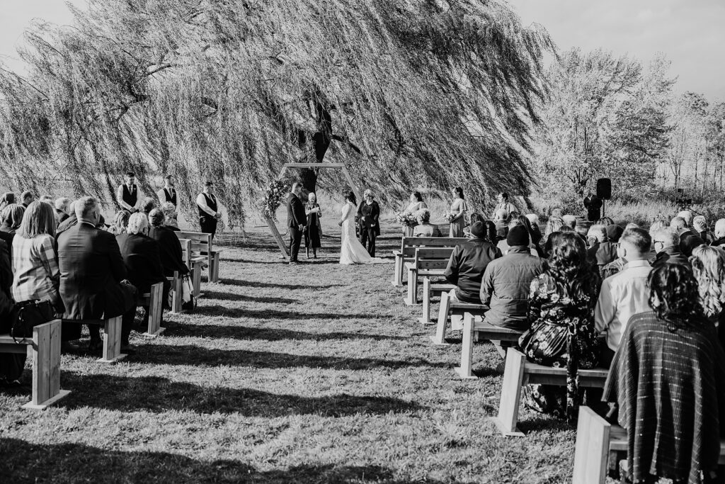 Black and white image of a bride and groom exchanging vows at their outdoor wedding ceremony at crescent hill acres.