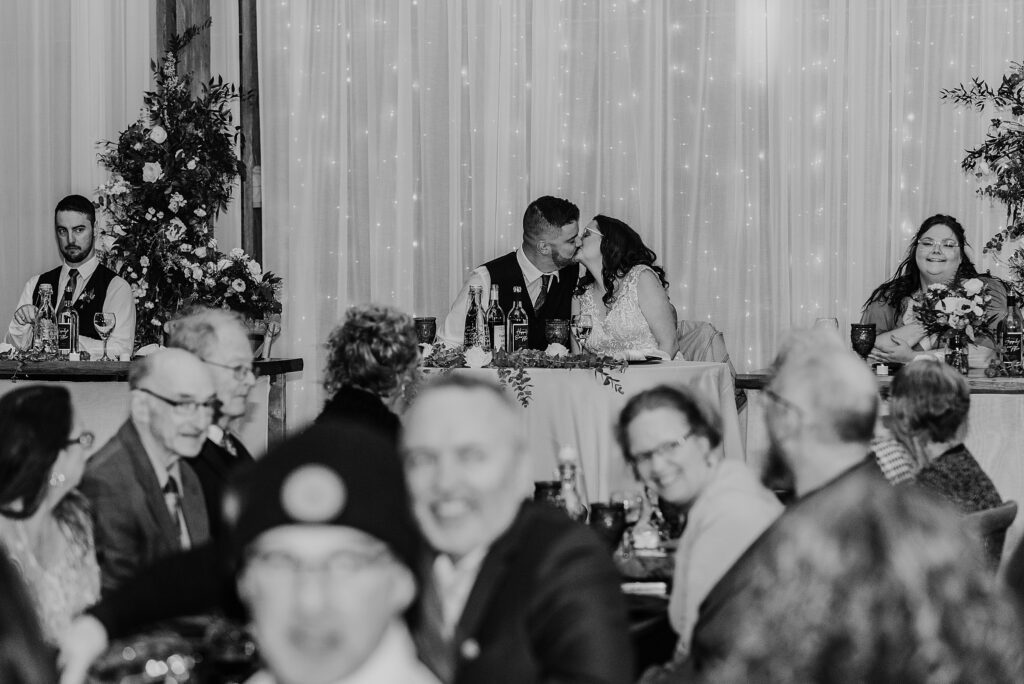 Bride and groom share a kiss at a sweetheart table at their Crescent Hill Acres wedding reception. Captured by top sarnia wedding photographer ashlee ellison.